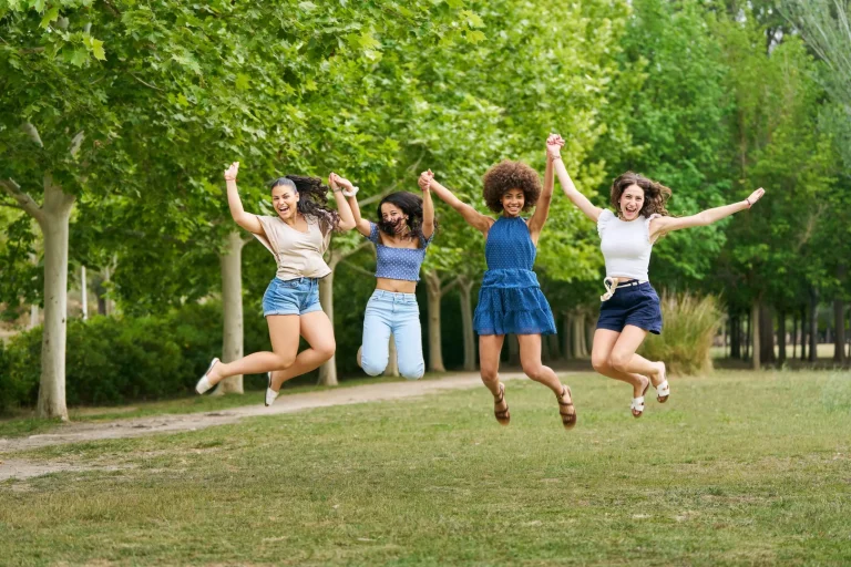 Vier junge Frauen springen gemeinsam in einem Park